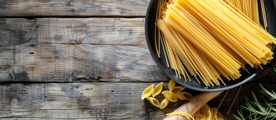 Poster - Uncooked pasta in a pan on a rustic wooden backdrop showcasing a copy space image