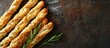 © HN Works - Italian breadsticks seasoned with rosemary and salt on a dark brown stone surface captured from above leaving room for additional content such as a copy space image