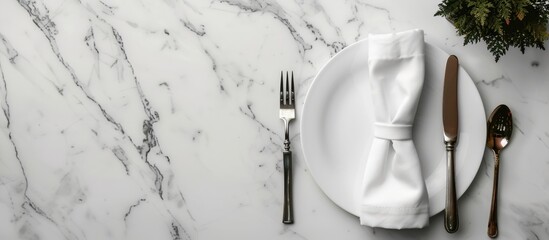 Wall Mural - Top view of a chic dining arrangement with silverware and napkin on a white marble table alongside a designated copy space image