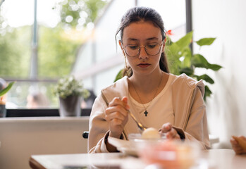 Portrait of a caucasian teenage girl with ice cream in a cafe.