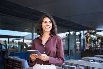 Wall Mural - Young latin Hispanic adult professional business woman looking at online trade app. European mature businesswoman CEO holding digital tablet using fintech tab application working in workspace office