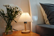© DragonImages - Close-up of bedside table with lamp and bouquet of flowers in bedroom