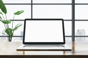 Poster - Modern laptop with blank screen on wooden desk in office with city view. 3D Rendering