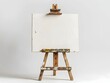 © pavlofox - Empty canvas on wooden easel against a light gray background in a creative studio