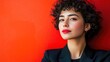 © Iswanto - Close up portrait of a young woman with curly hair, wearing a black blazer, against a red background.