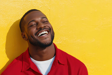 Black Man in Red Shirt and White T-Shirt, Laughing Joyfully on a Sunny Day, Close-Up Portrait with Sunlight and Yellow Wall Backdrop
