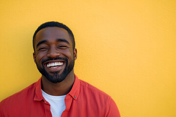 High-Resolution Portrait of a Laughing Black Man in a Red Shirt and White T-Shirt, Illuminated by Sunlight with a Yellow Wall Background
