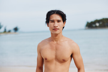 Wall Mural - Smiling Asian Muscular Man Enjoying Tropical Beach Vacation