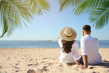 Poster - Couple relaxing under palm leaves on tropical beach