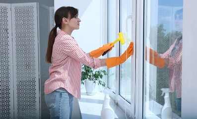 Sticker - Beautiful young housewife with squeegee cleaning window indoors