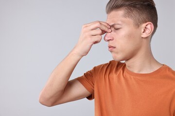 Sticker - Young man suffering from sinusitis on light grey background, space for text