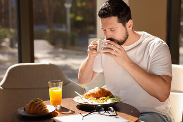 Poster - Handsome man having tasty breakfast in cafe