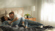 © Yuliia - Happy couple family man jumping bed woman husband wife girl guy bedroom home together hugging laugh smile fun embrace cuddle honeymoon lovers bond feelings closeness sweetheart female male romantic