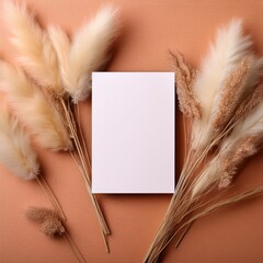 Poster - A flat lay photo of a white card surrounded by dried pampas grass on a peach background