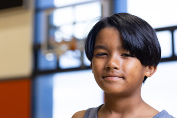 Wall Mural - Smiling boy in school gymnasium with basketball hoop in background