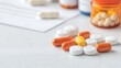 © TEERAPAT - Close-up of a selection of medicine pills and tablets on a clean, white surface with a few pill bottles and a prescription paper partially visible in the background, depicting a professional pharmacy