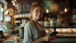 © gfx_yasir - A smiling woman with brown hair is standing behind a counter in a cafe
