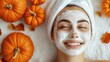 © Artyom - Smiling woman with facial mask surrounded by pumpkins
