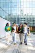 © Daniel - Vertical image of multiracial happy university students walking to class together laughing and talking.
