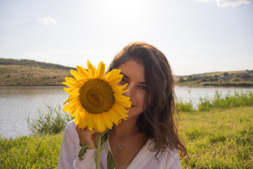 A smiling girl holds a sunflower in her hand next to the face