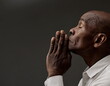 © herlanzer - man praying to god with hands together Caribbean man praying with black grey background with people stock image stock photo