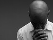 © herlanzer - man praying to god with hands together Caribbean man praying with black grey background with people stock image stock photo