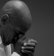 © herlanzer - man praying to god with hands together Caribbean man praying with black grey background with people stock image stock photo