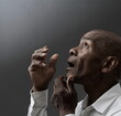© herlanzer - man praying to god with hands together Caribbean man praying with black grey background with people stock image stock photo