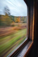 Poster - A window in an old-fashioned train car, capturing the motion blur of passing fields.