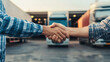 © Maciej Koba - Two men shaking hands in front of trucks at a logistics center