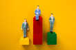 © chee siong teh - Three businessmen figurines are standing on different level block towers representing the concept of business competition and success
