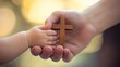 © Pricha.RT - Close-up of a mother's hand holding her child's hand, with a Christian cross, conveying the nurturing and faith-filled journey of life.