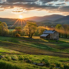 A perfect Spring day ends as the sun sets and sprays warm golden light over a beautiful farm with fields sprouting, a stone house, and mountain ridges in the background