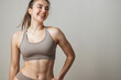 © Alienmonster Images - Cheerful woman in neutral-tone fitness wear, smiling and posing confidently, showcasing her toned body in a well-lit, minimalist indoor setting, with a soft background that provides ample copy space,