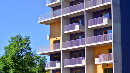 New modern block of flats in green area. Eco apartment building saving energy and fresh air concept. Green tree and new apartment building. The harmony of nature and modernity.