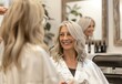 © kinara art design - A woman with styled hair smiles in a salon, enjoying a beauty treatment.