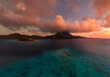 © Mat Hayward - Puffy pink and orange colorful clouds over Mount Otemanu on tropical island Bora Bora. Clear azure south pacific ocean water reveals a coral reef during sunrise.