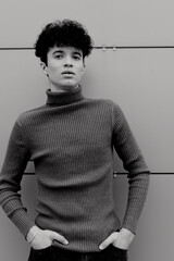 Wall Mural - Young man in black and white turtleneck sweater standing in front of wall with hands in pockets