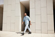 © SHOTPRIME STUDIO - Confident young man walking out of modern building in stylish casual attire, showcasing independence and urban lifestyle