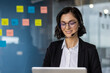 © Liubomir - Businesswoman wearing headset smiling while working on laptop computer. Customer service agent or support representative in office. Communication and technology concepts woman using phone.