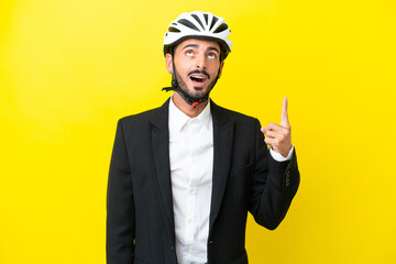 Business caucasian man with a bike helmet isolated on yellow background pointing up and surprised