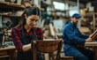 © Cetin - woman working on shining up an old chair in her workshop while another man works behind
