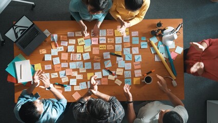 Top view of manager looking at idea on sticky notes and explain idea about web design. Skilled marketing team or programmer brainstorming idea while looking at tablet with color palette. Symposium.
