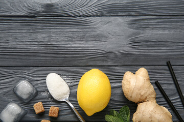 Wall Mural - Lemon with mint, ginger and ice cubes on black wooden background