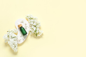 Wall Mural - Bottle of essential oil with beautiful lilac flowers on pale yellow background