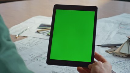 Hand holding green screen tablet watching video at corporate workplace closeup.