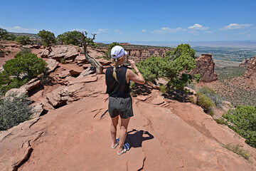 Wall Mural - Woman photographing and enjoying scenery of Colorado National Monument near Fruita, Colorado on clear sunny summer day..