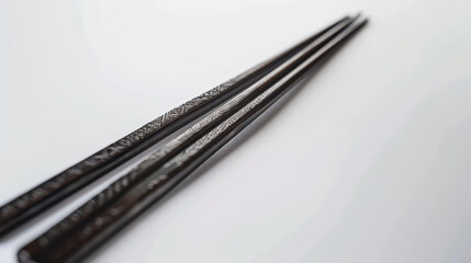 Metal chopsticks with engraved patterns cut out on a clean white background.