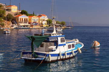 Wall Mural - Colourful house facades and fishing boats in the bay of Symi village at sunset.