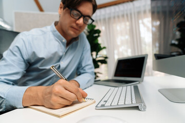 Stressful IT developer analyzing online software development information on pc and laptop with coding program on trial application project. Technical engineer writing crucial memo lists. Pecuniary.